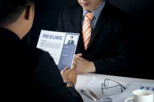 Candidate presenting resume during job interview at office desk