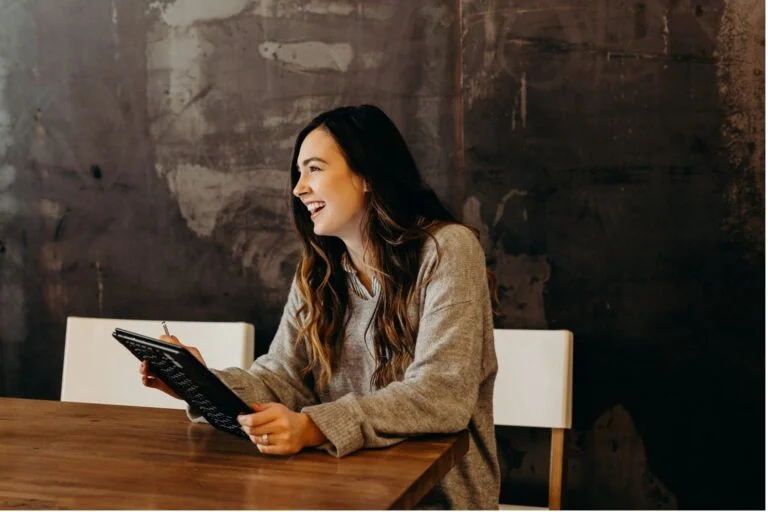Professional woman smiling while working on a laptop, representing Horizon’s recruitment services.