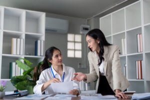 Professional women discussing documents in modern office setting
